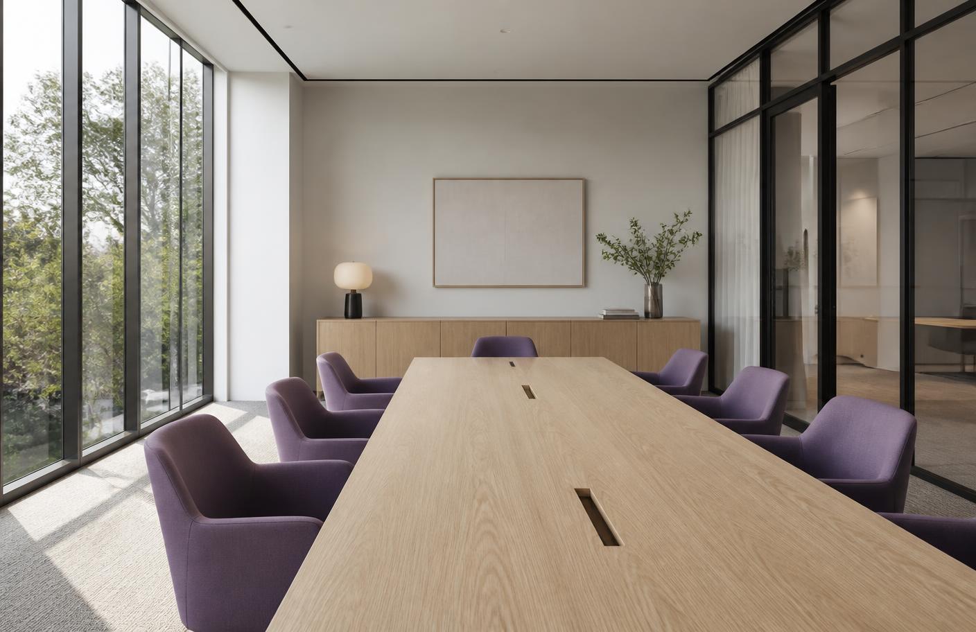 A calm, empty modern boardroom with pale oak table and purple chairs